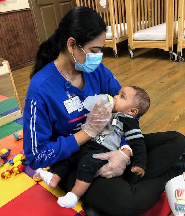 Caregiver giving an infant a bottle.