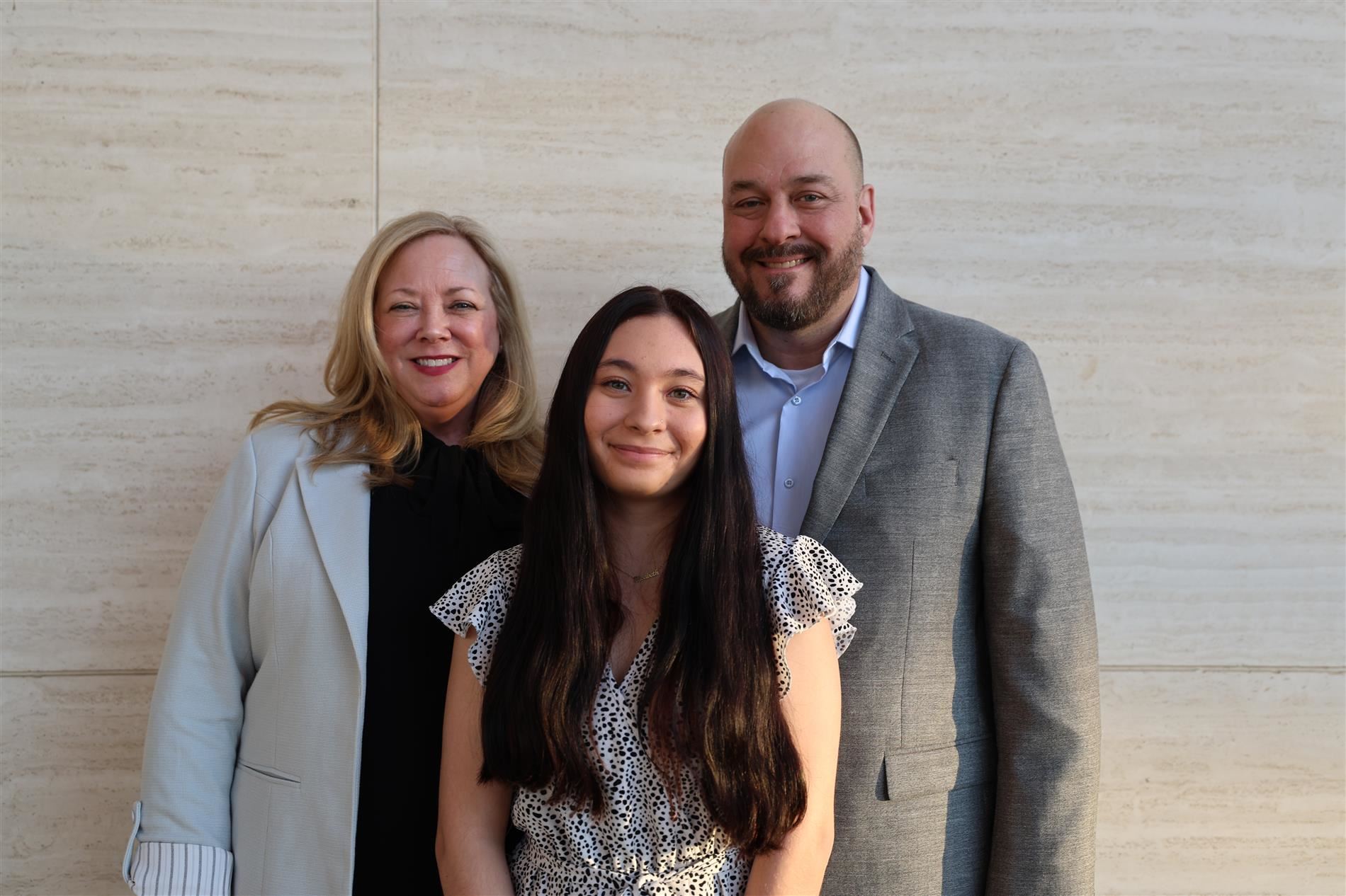 Stacie Burk with her family smiling in front of a stone backdrop
