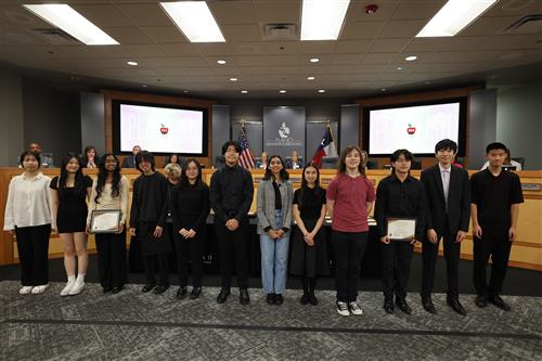 Students standing at the front of the board of trustees for their musical achievements