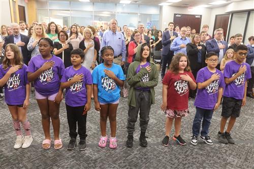 8 students with hands over their chest performing the pledge of allegiance