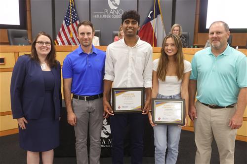 5 individuals posing for a picture, the middle two have recognition certificates