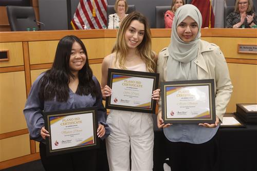 three individuals posing with recognition certificates