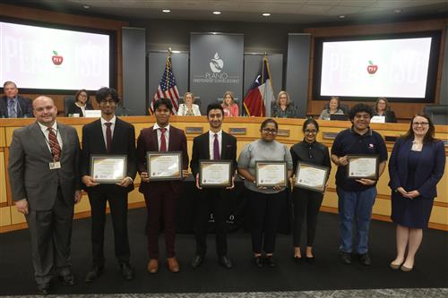 8 individuals smiling, with the middle six holding recognition certificates