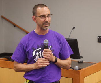  man in purple shirt holding microphon
