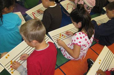Group of students placing dots on music staff. 